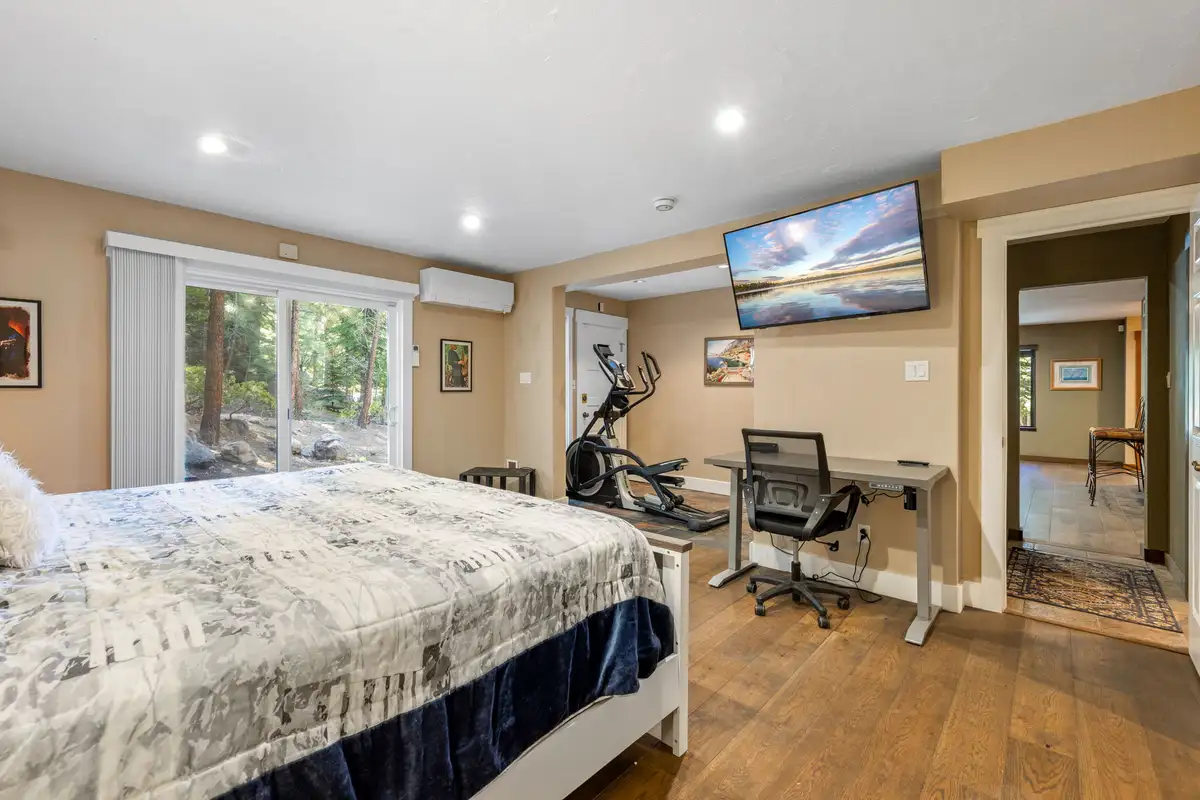 Bedroom with a bed, desk, exercise bike and wall TV, Tranquil Stay