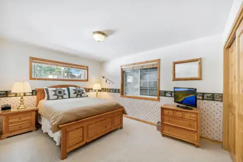 Bedroom with a wood bed and small TV, Hastings Hideaway Cabin
