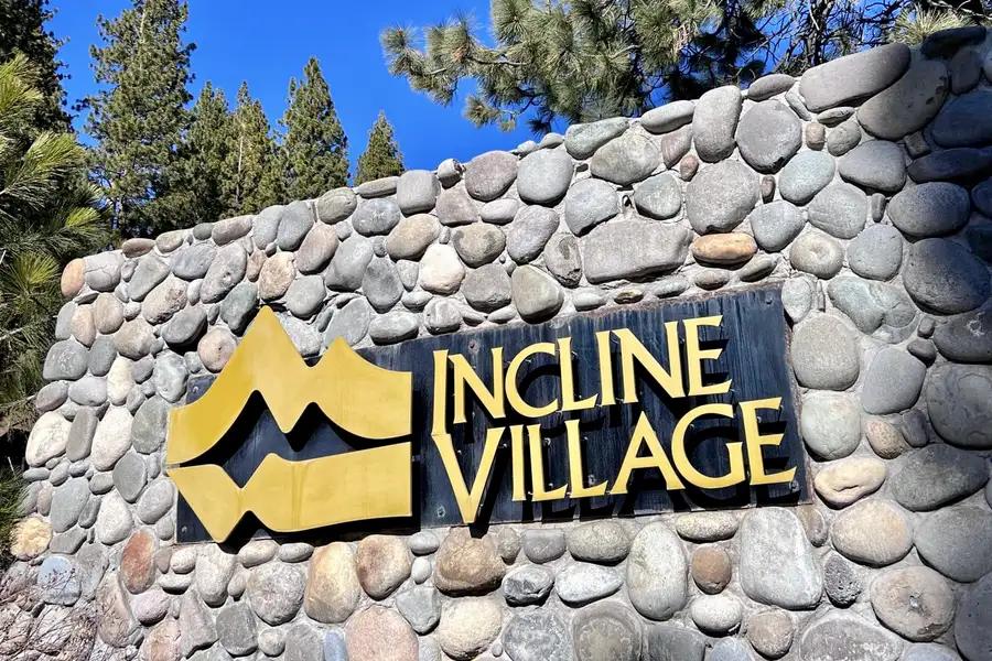 River rock entrance sign with a gold logo, Sunlit Incline Retreat