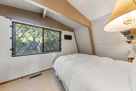 A-frame bedroom with a white bed and diamond-pane window, Livin' on the Edge