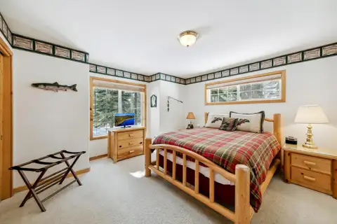 Bedroom with a log bed and plaid bedding, Hastings Hideaway Cabin