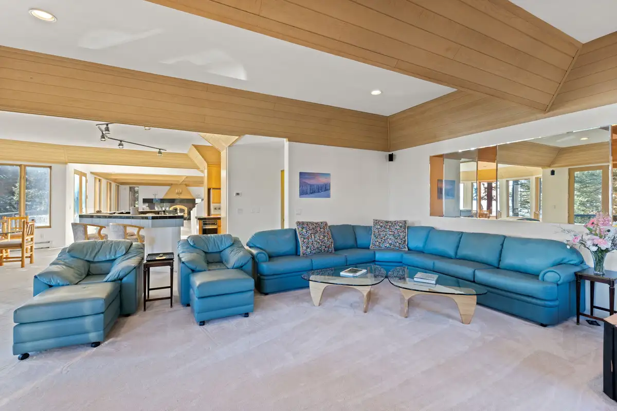 Living room with teal leather sectional and glass tables, 90s Tahoe Time Capsule